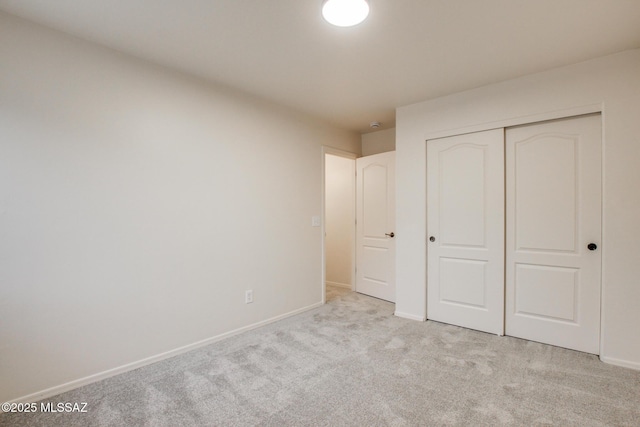 unfurnished bedroom featuring baseboards, carpet floors, and a closet