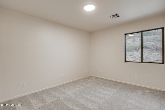 spare room with visible vents, light colored carpet, and baseboards