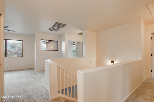 hall featuring an upstairs landing, carpet flooring, baseboards, and visible vents
