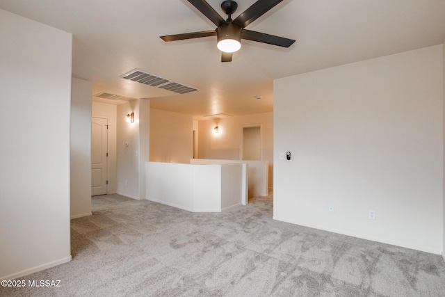 carpeted spare room with visible vents, baseboards, and a ceiling fan