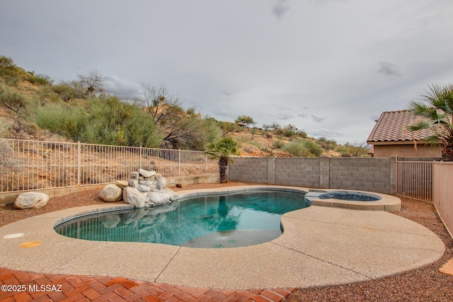 view of pool with a fenced backyard and a pool with connected hot tub