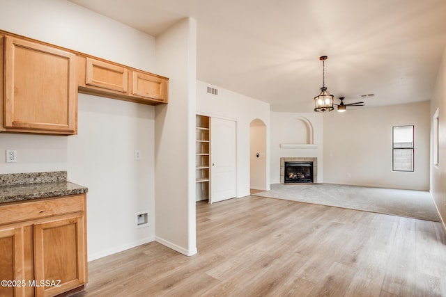 kitchen featuring dark stone counters, arched walkways, visible vents, and light wood finished floors