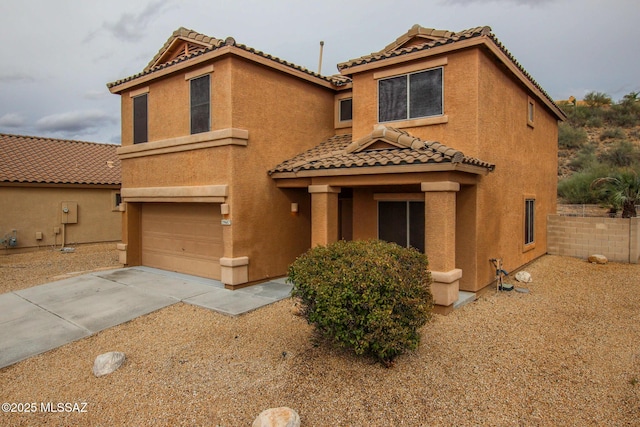 mediterranean / spanish-style house featuring a tiled roof, stucco siding, driveway, and a garage