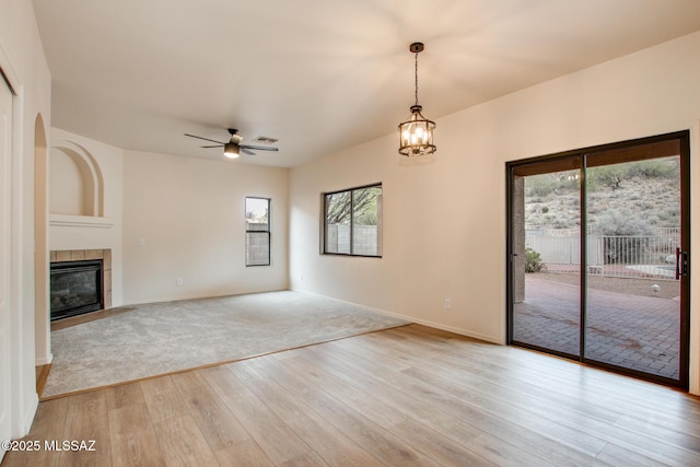 unfurnished living room with light wood-style floors, visible vents, a wealth of natural light, and a tile fireplace