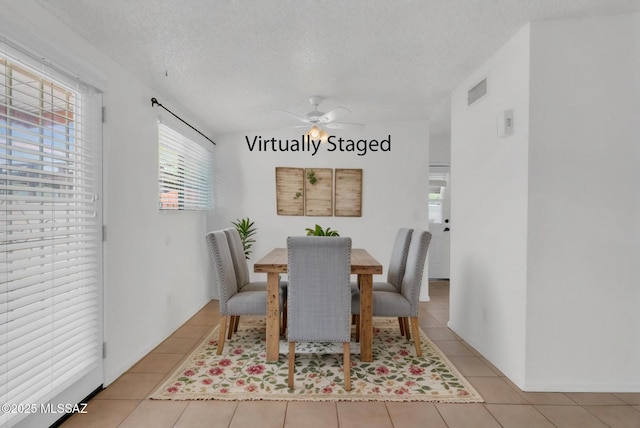 dining area with a textured ceiling, ceiling fan, and tile patterned flooring