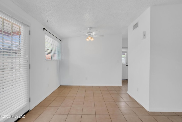 unfurnished room featuring light tile patterned floors, visible vents, a textured ceiling, and ceiling fan