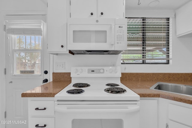 kitchen featuring white cabinetry, dark countertops, and white appliances