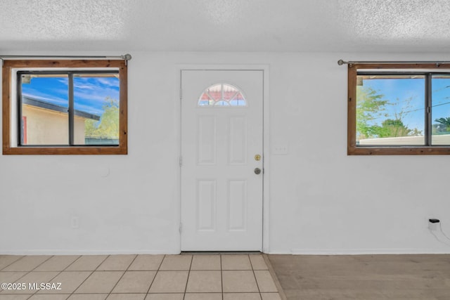 foyer entrance featuring light tile patterned floors, baseboards, and a textured ceiling