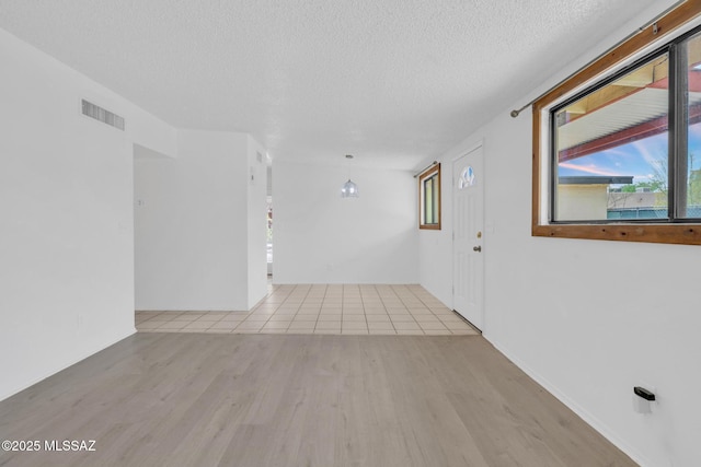 spare room with visible vents, wood finished floors, and a textured ceiling