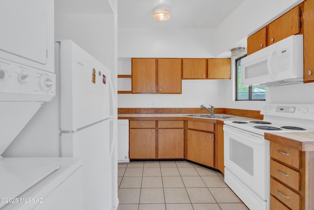 kitchen with stacked washer and clothes dryer, white appliances, light tile patterned floors, light countertops, and a sink
