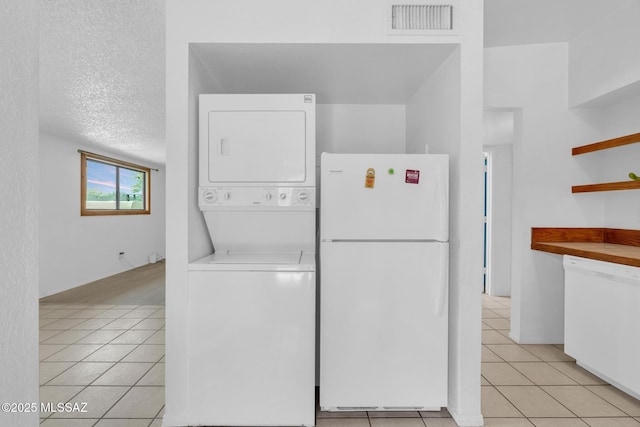 washroom with light tile patterned floors, visible vents, and stacked washer / drying machine