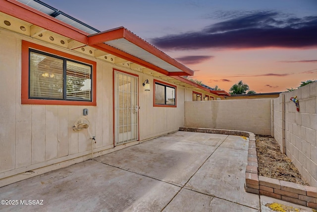 patio terrace at dusk featuring a fenced backyard