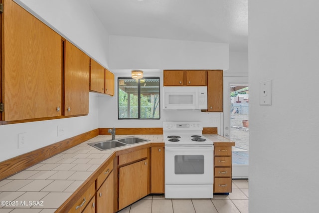 kitchen featuring tile counters, a sink, white appliances, and a wealth of natural light
