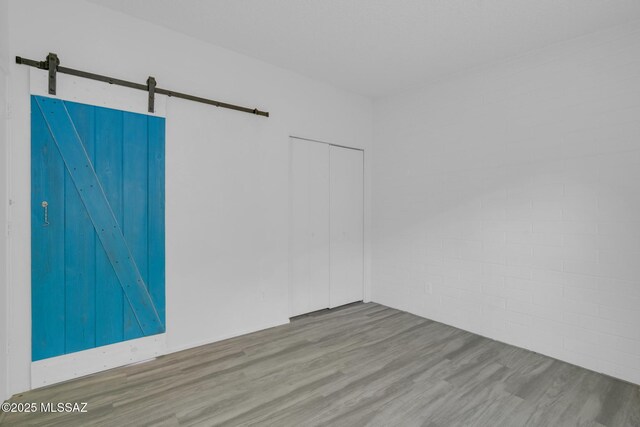 empty room with wood finished floors and a barn door