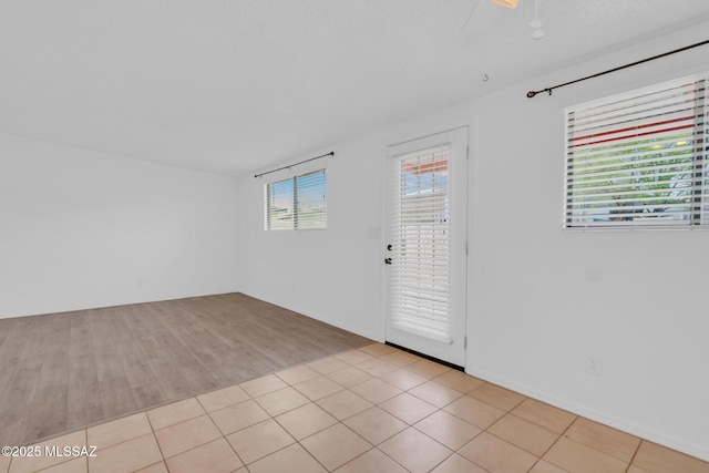 empty room with light tile patterned floors and a ceiling fan