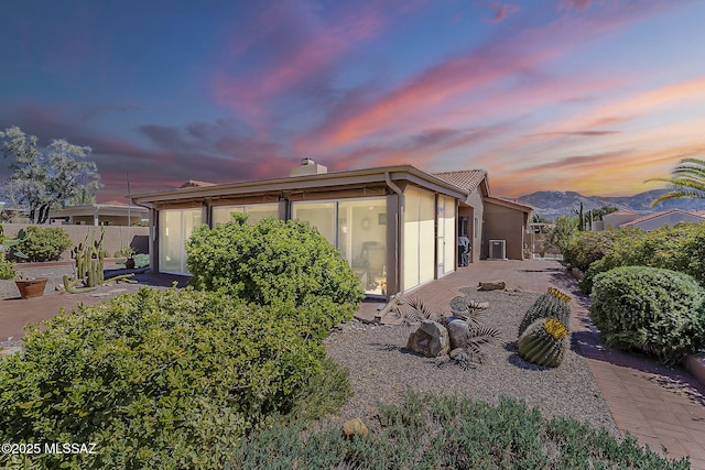 view of side of property featuring a mountain view, a chimney, and stucco siding