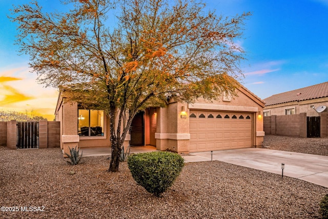 view of front of property with driveway, a gate, stucco siding, fence, and a garage
