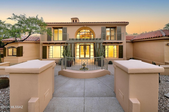 7222 E Desert Moon Loop, Tucson, AZ 85750 - back of property at dusk with french doors, a balcony, stucco siding, and a tile roof
