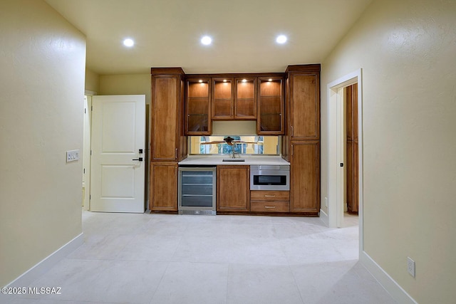 7222 E Desert Moon Loop, Tucson, AZ 85750 - kitchen with wine cooler, baseboards, glass insert cabinets, brown cabinetry, and recessed lighting