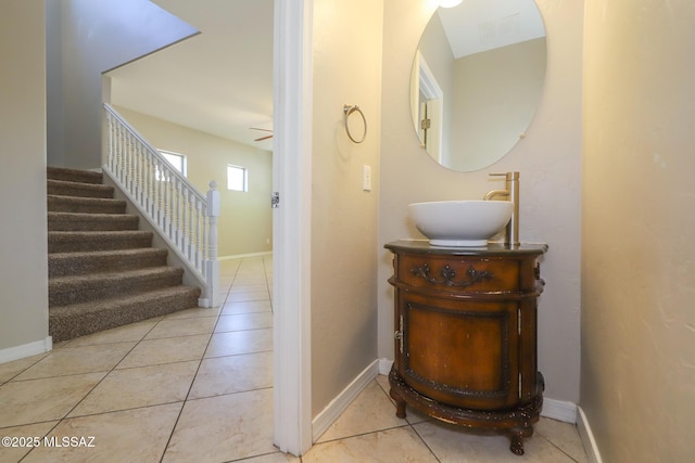 corridor featuring tile patterned flooring, baseboards, a sink, and stairway