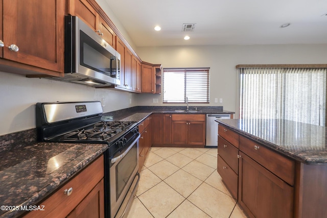 kitchen featuring dark stone countertops, open shelves, light tile patterned floors, a sink, and appliances with stainless steel finishes