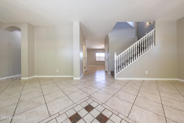spare room featuring stairway, tile patterned flooring, and baseboards