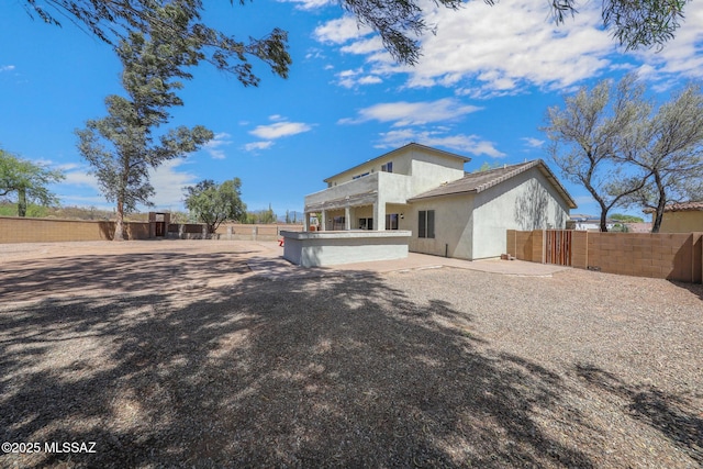 rear view of house featuring fence and stucco siding