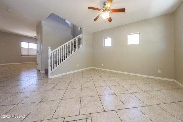 empty room featuring stairway, ceiling fan, baseboards, and light tile patterned flooring