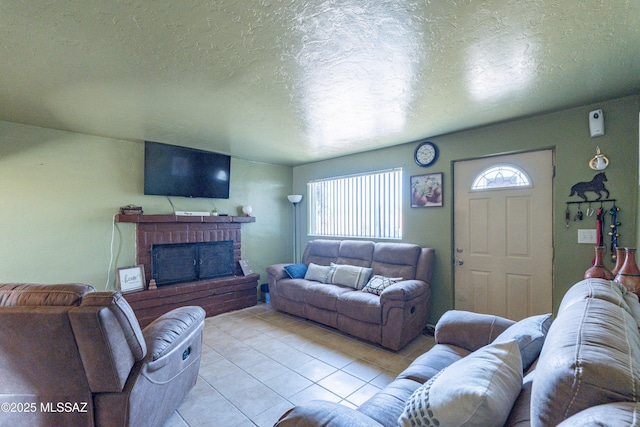 living room featuring light tile patterned flooring, a textured ceiling, and a brick fireplace