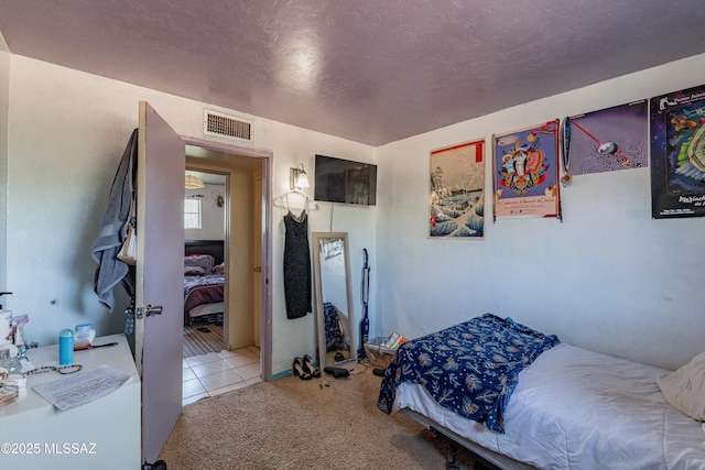 carpeted bedroom featuring tile patterned floors, a textured ceiling, and visible vents