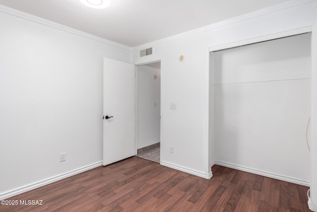 unfurnished bedroom featuring wood finished floors, ornamental molding, baseboards, and visible vents
