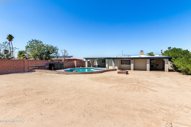 rear view of property with a fire pit, a patio area, a fenced in pool, a chimney, and a fenced backyard