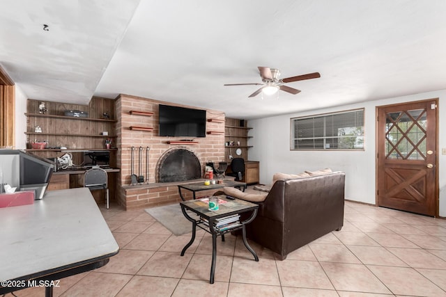 living area with a fireplace, ceiling fan, and light tile patterned floors