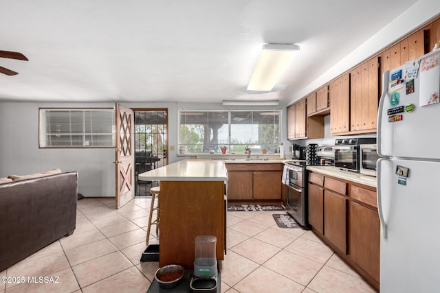 kitchen with light tile patterned flooring, range with two ovens, light countertops, and freestanding refrigerator