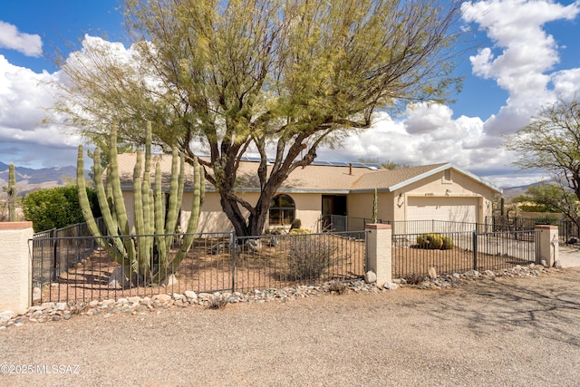 ranch-style house featuring concrete driveway, stucco siding, an attached garage, a fenced front yard, and a gate