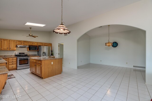 kitchen featuring a center island, under cabinet range hood, visible vents, stainless steel appliances, and arched walkways