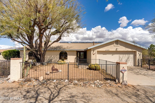 single story home featuring concrete driveway, stucco siding, a fenced front yard, a garage, and roof mounted solar panels