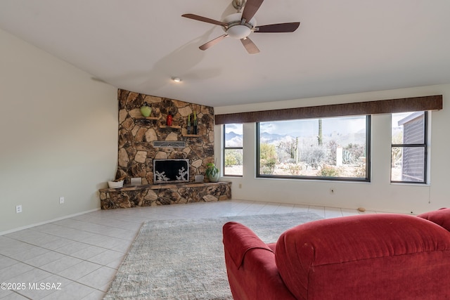 living area featuring tile patterned flooring, a stone fireplace, a ceiling fan, and a healthy amount of sunlight