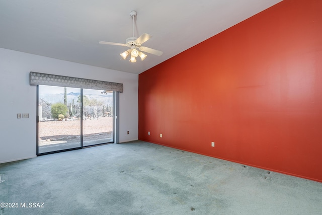 carpeted empty room featuring baseboards, a ceiling fan, and vaulted ceiling