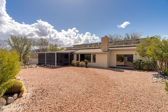 rear view of house with a sunroom and stucco siding