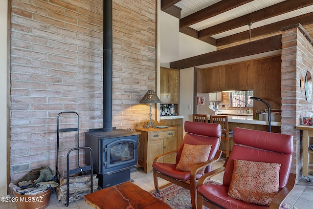 sitting room featuring beamed ceiling, a wood stove, brick wall, and light tile patterned floors