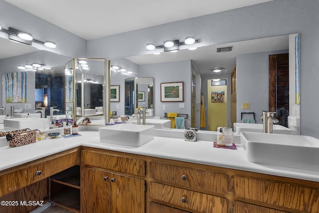 bathroom featuring a shower stall, double vanity, visible vents, and a sink