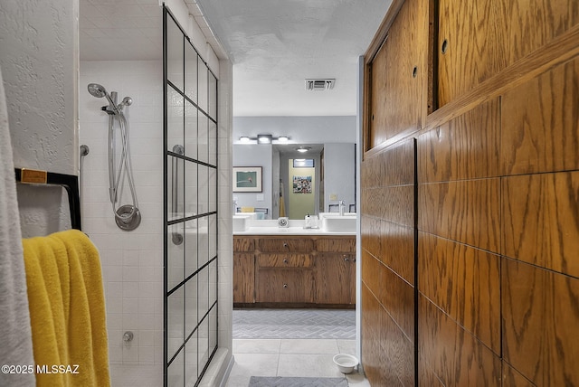 full bathroom featuring double vanity, visible vents, tile patterned floors, and a walk in shower