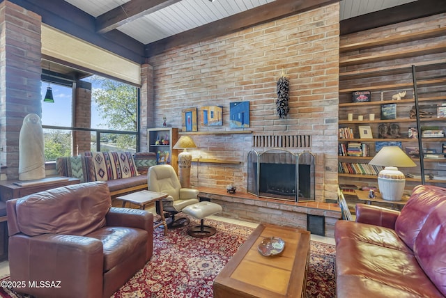 living room with an outdoor brick fireplace, visible vents, beamed ceiling, and brick wall