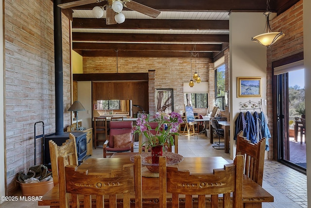 dining area featuring a wood stove, a high ceiling, brick wall, beamed ceiling, and ceiling fan