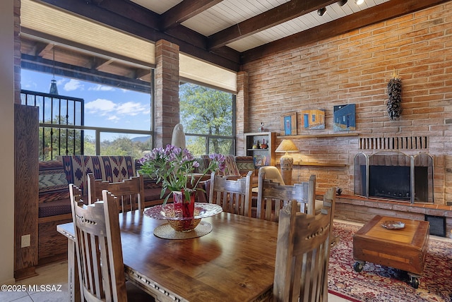 dining area featuring an outdoor brick fireplace and beam ceiling