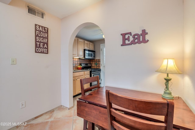 dining space with light tile patterned floors, arched walkways, and visible vents