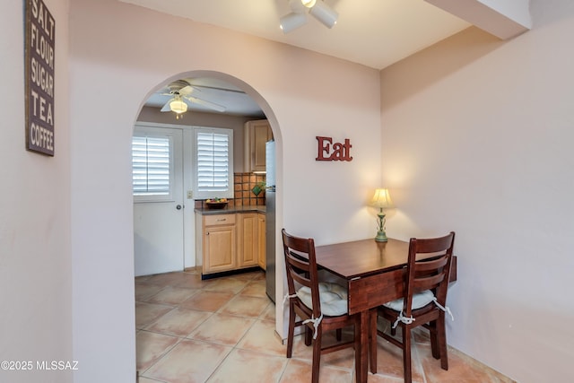 dining space with arched walkways, ceiling fan, and light tile patterned flooring