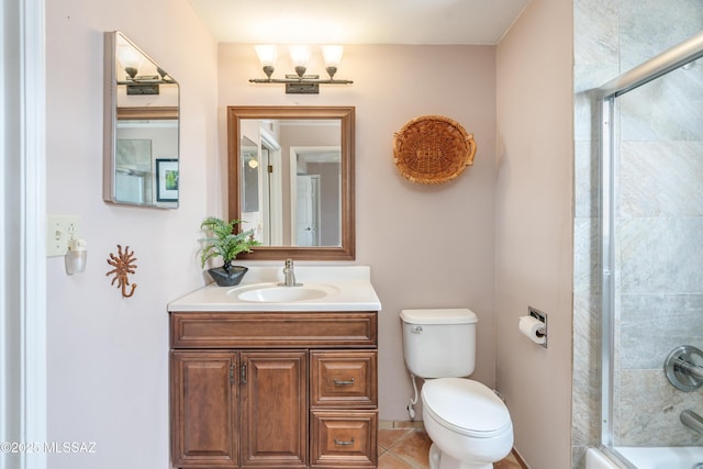 bathroom featuring tile patterned flooring, combined bath / shower with glass door, toilet, and vanity