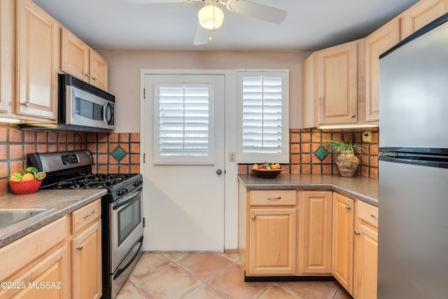 kitchen featuring light brown cabinetry, backsplash, appliances with stainless steel finishes, and light tile patterned floors